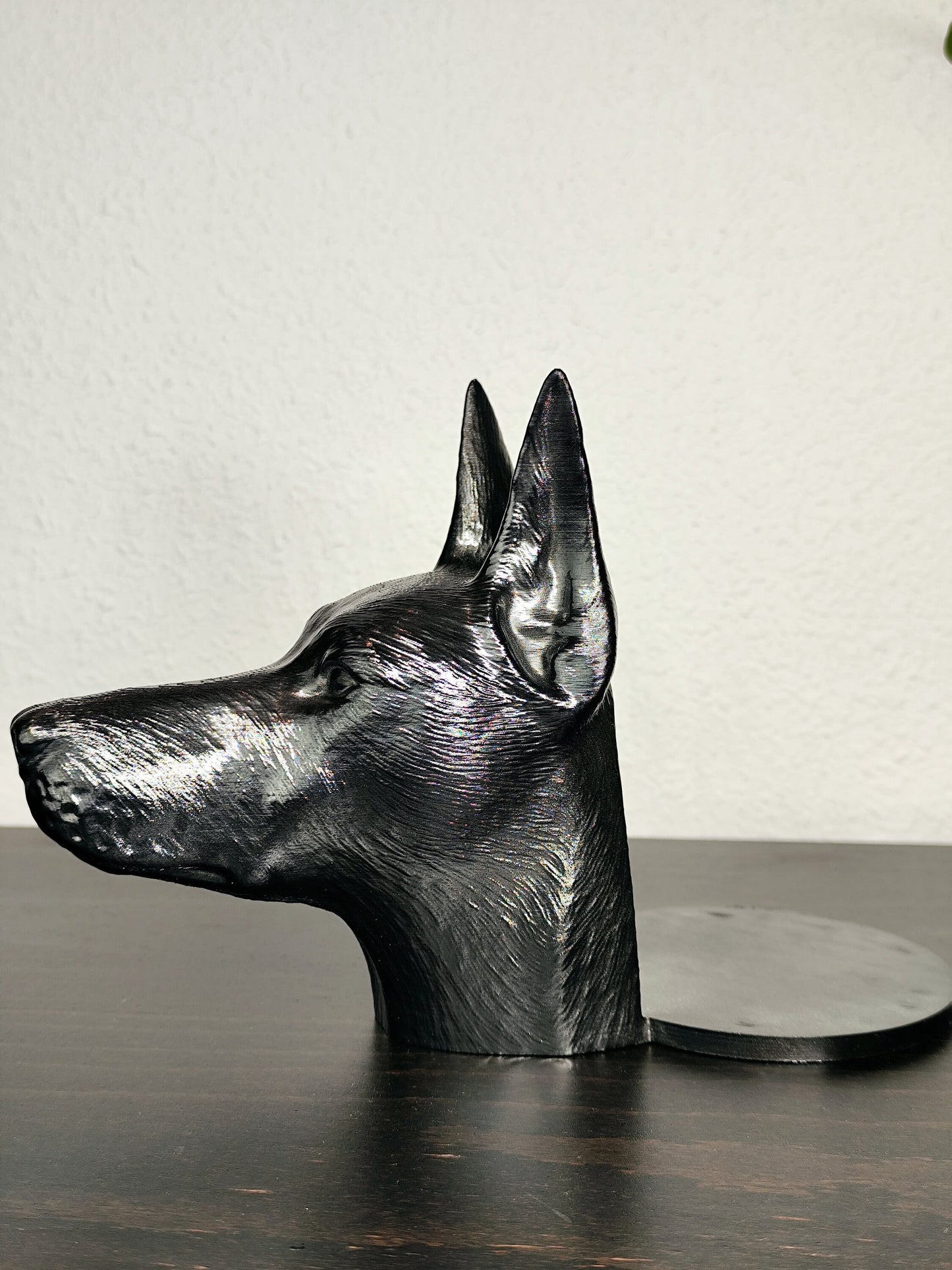 Close-up of a hand-painted Doberman planter featuring metallic gold and silver detailing, with a small green plant in the background. The planter captures the lifelike features of a Doberman&#39;s head with intricate details