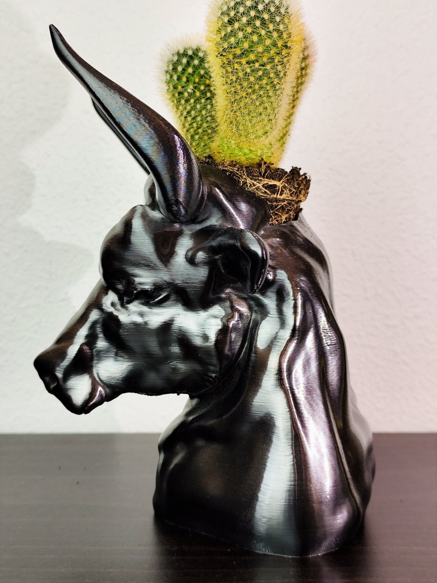 Hand-painted metallic bull head planter with gold accents, designed for holding succulents, displayed on a dark wooden surface