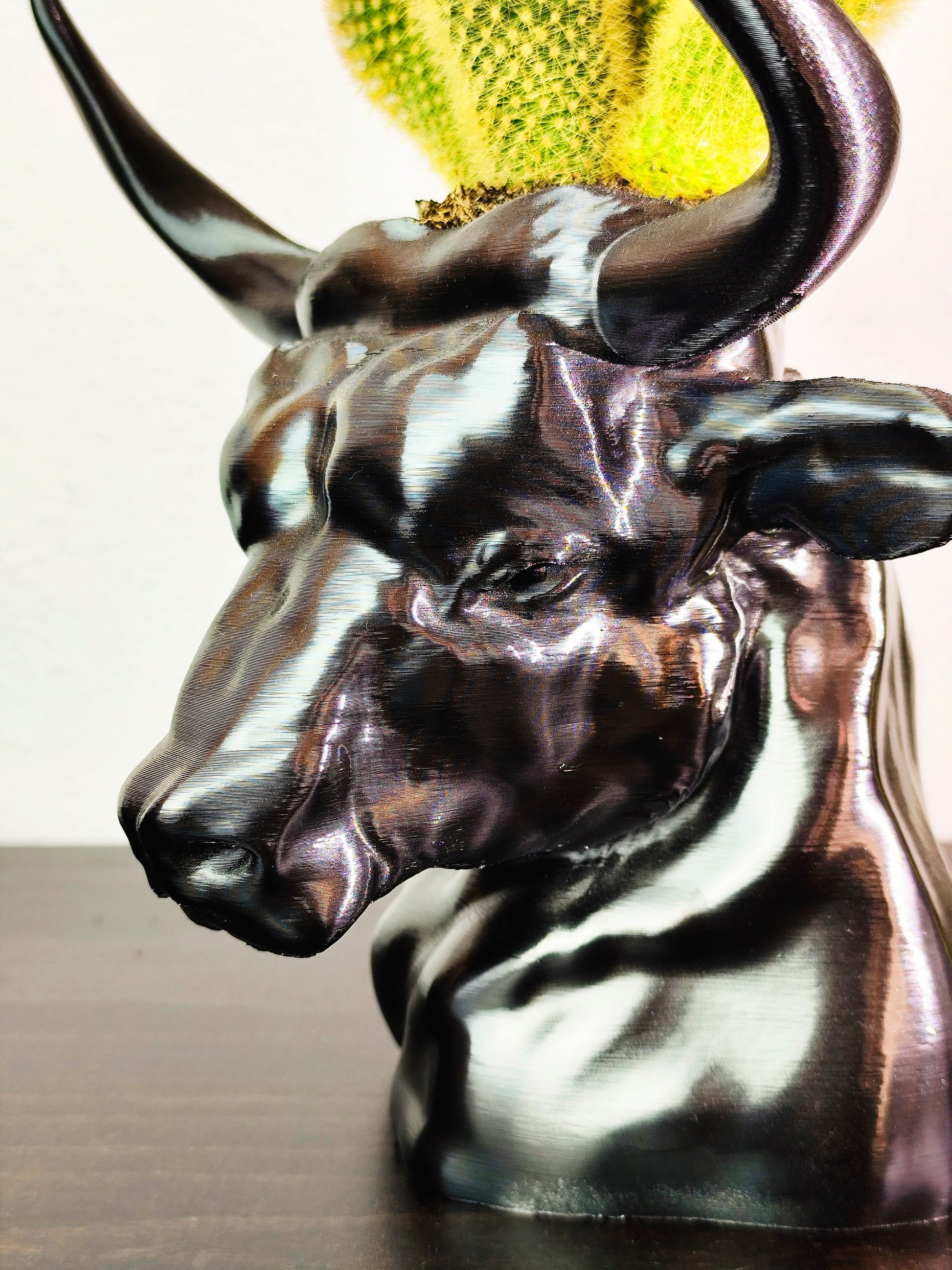 Hand-painted metallic bull head planter with gold accents, designed for holding succulents, displayed on a dark wooden surface