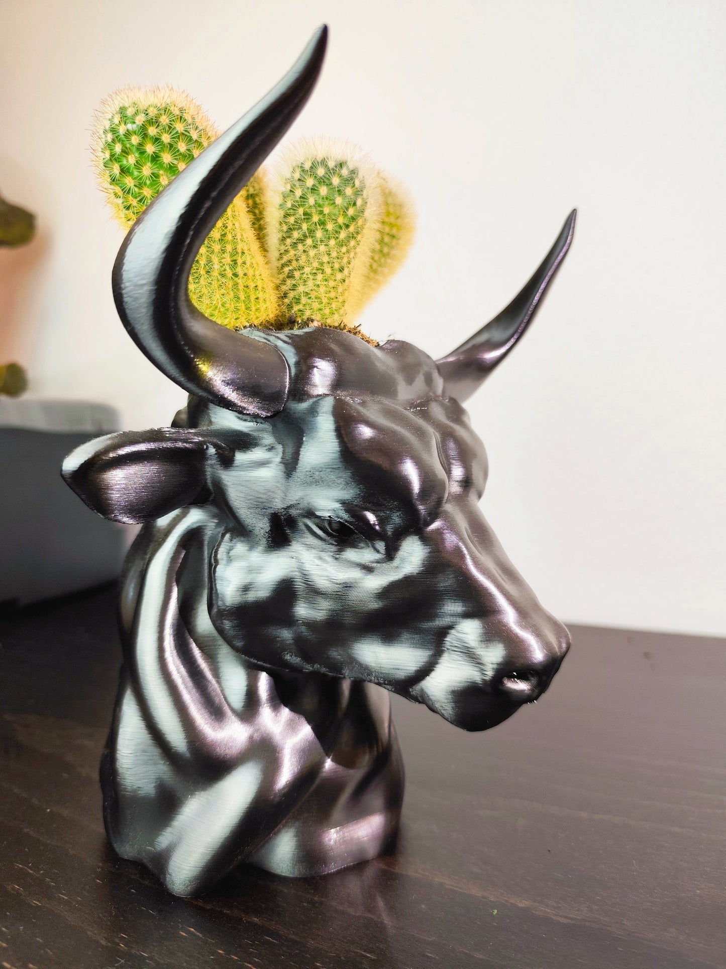 Side view of a metallic bull head planter with lifelike details and horns, suitable for showcasing small plants or succulents